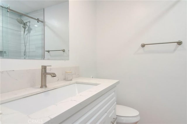 bathroom featuring vanity, toilet, and walk in shower