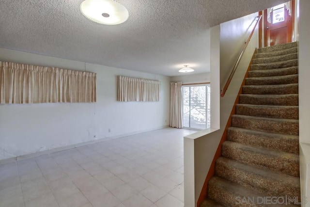 stairway featuring a textured ceiling