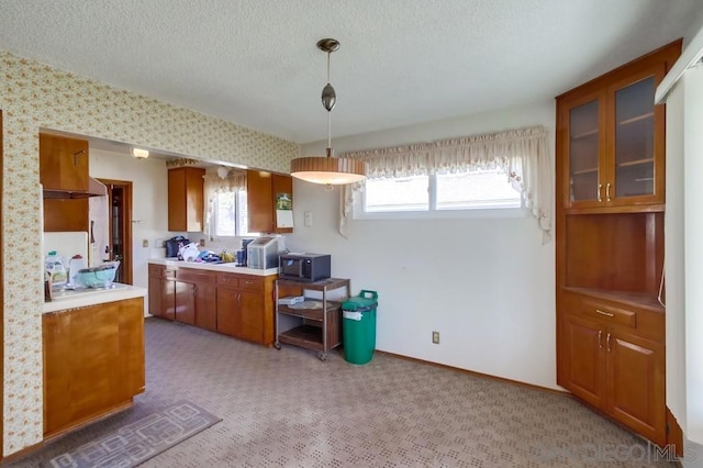 kitchen featuring hanging light fixtures, carpet floors, wall chimney range hood, and a textured ceiling