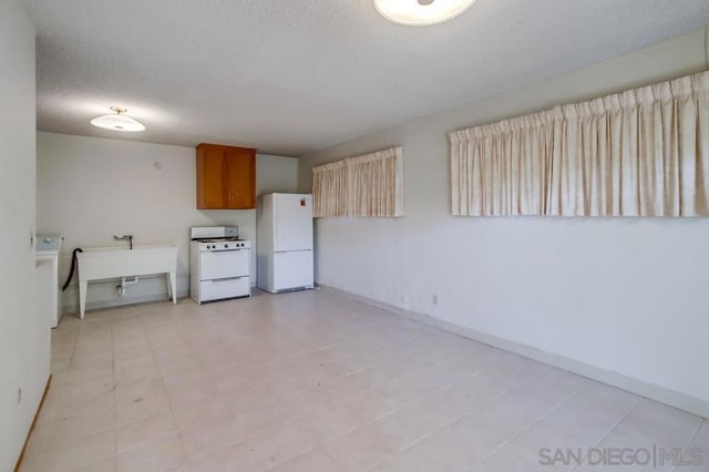 kitchen with white appliances, washer / clothes dryer, sink, and a textured ceiling