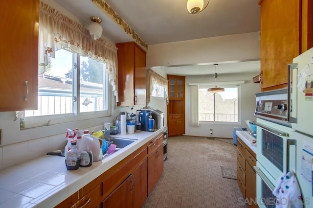 kitchen featuring pendant lighting, tile countertops, oven, and a healthy amount of sunlight