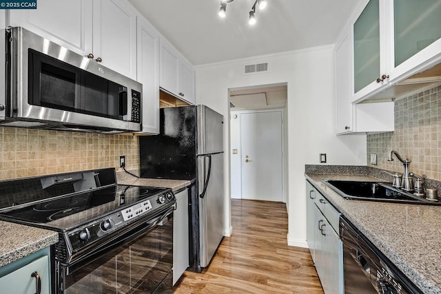 kitchen with sink, white cabinetry, tasteful backsplash, black appliances, and light stone countertops