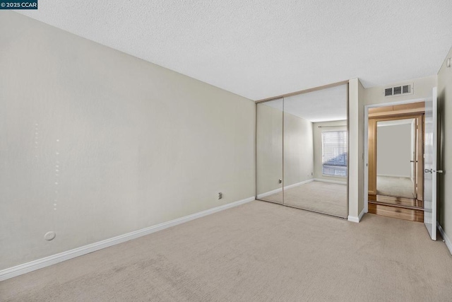 unfurnished bedroom with light carpet, a closet, and a textured ceiling