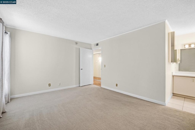 unfurnished room with light colored carpet and a textured ceiling