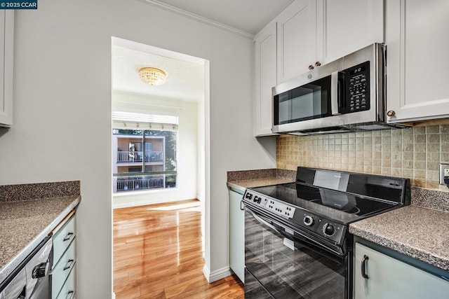 kitchen with white cabinetry, backsplash, stainless steel appliances, crown molding, and light hardwood / wood-style flooring