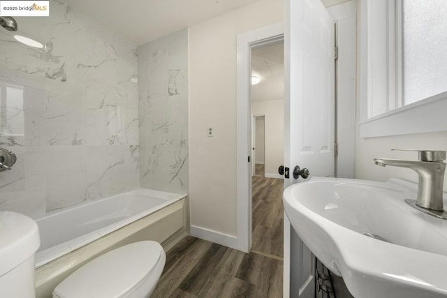 full bathroom featuring tiled shower / bath, sink, hardwood / wood-style floors, and toilet