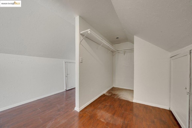 walk in closet with lofted ceiling and dark hardwood / wood-style flooring