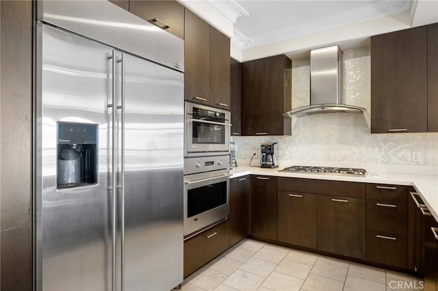 kitchen with wall chimney range hood, crown molding, appliances with stainless steel finishes, light tile patterned flooring, and decorative backsplash