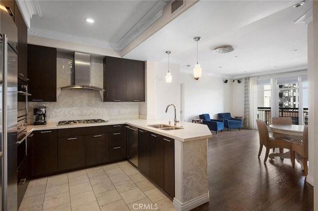 kitchen featuring sink, crown molding, kitchen peninsula, stainless steel appliances, and wall chimney range hood