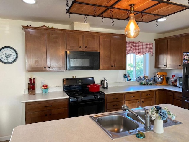 kitchen with decorative light fixtures, sink, and black appliances