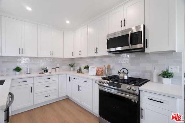 kitchen featuring decorative backsplash, stainless steel appliances, light hardwood / wood-style flooring, and white cabinets