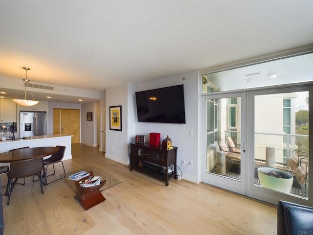 living room with sink, french doors, and light wood-type flooring