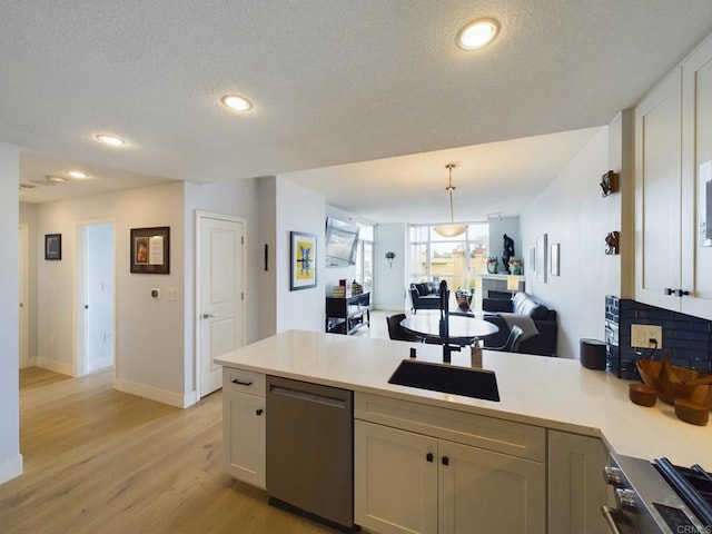 kitchen featuring decorative light fixtures, a textured ceiling, light wood-type flooring, black dishwasher, and kitchen peninsula