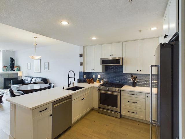 kitchen featuring stainless steel appliances, white cabinetry, sink, and kitchen peninsula