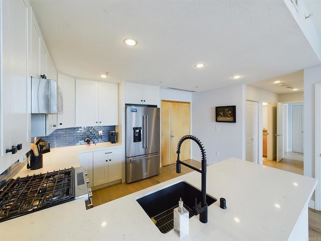 kitchen featuring tasteful backsplash, sink, high end refrigerator, white cabinets, and light hardwood / wood-style floors