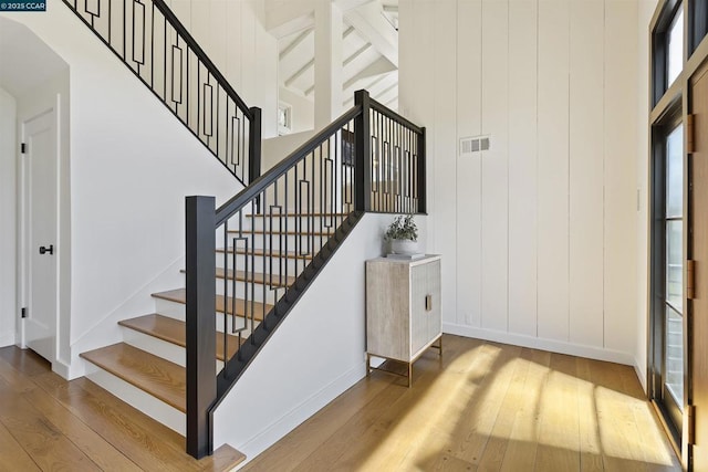 stairs with hardwood / wood-style floors and a high ceiling