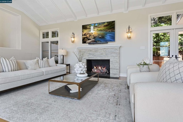 living room featuring hardwood / wood-style flooring, a stone fireplace, and vaulted ceiling with beams