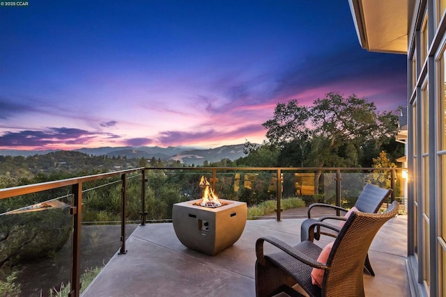 balcony at dusk featuring a mountain view and a fire pit