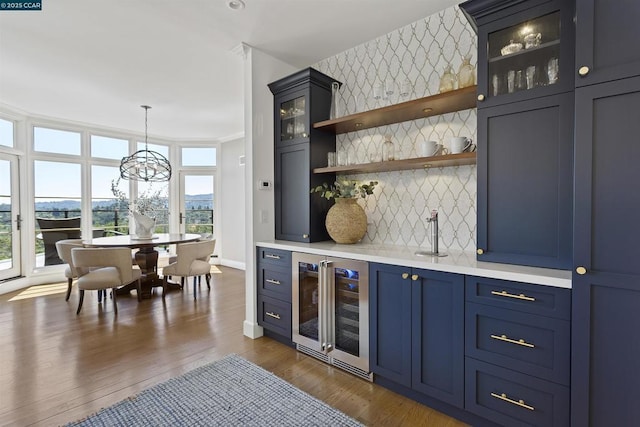 bar with hanging light fixtures, crown molding, dark wood-type flooring, and wine cooler