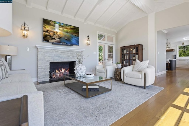 living room featuring wood-type flooring, a fireplace, lofted ceiling with beams, and a wealth of natural light