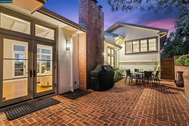 back house at dusk featuring a patio and french doors