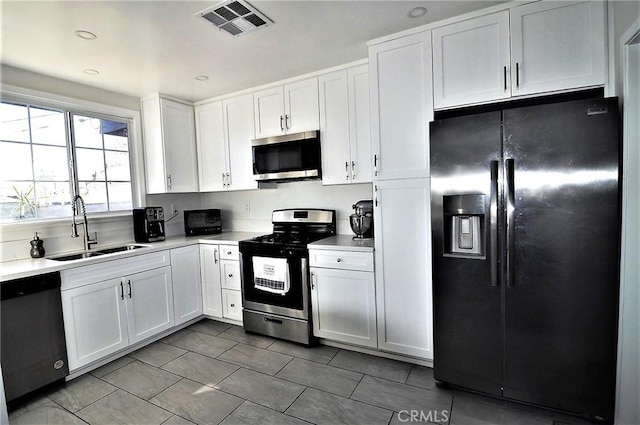 kitchen with appliances with stainless steel finishes, sink, white cabinets, and tile patterned floors