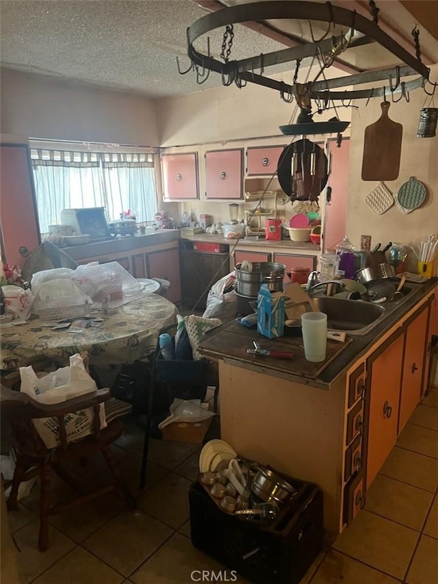 kitchen featuring light tile patterned flooring, refrigerator, sink, and a textured ceiling