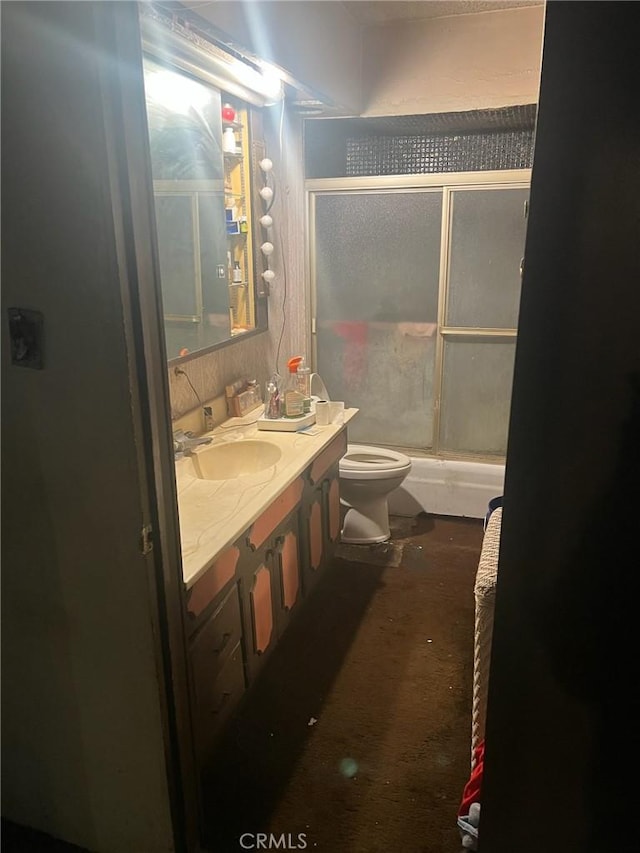 bathroom featuring a shower with door, vanity, and toilet