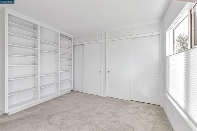 unfurnished bedroom featuring light colored carpet and multiple closets