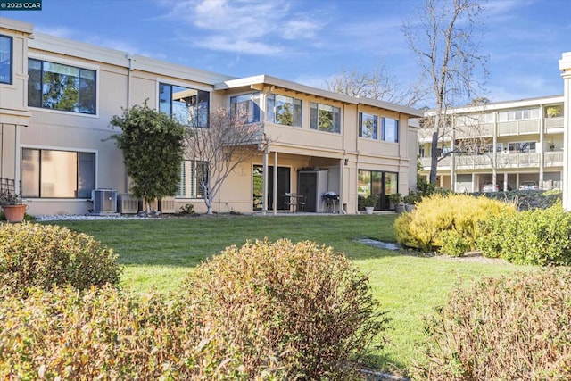 rear view of property featuring cooling unit and a lawn