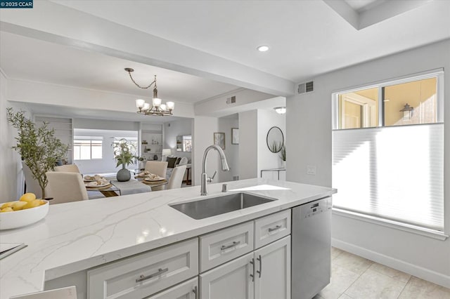 kitchen featuring sink, dishwasher, an inviting chandelier, hanging light fixtures, and light stone countertops