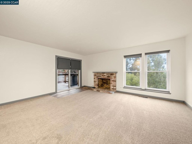 unfurnished living room with carpet flooring and a brick fireplace