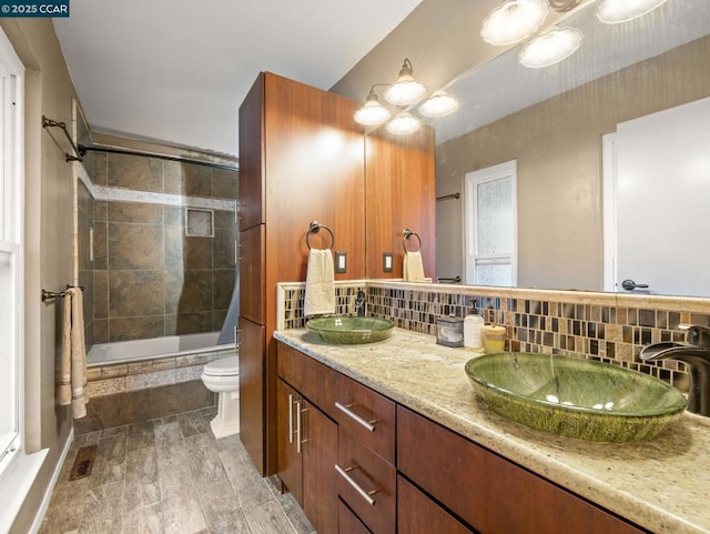 bathroom featuring vanity, decorative backsplash, and toilet