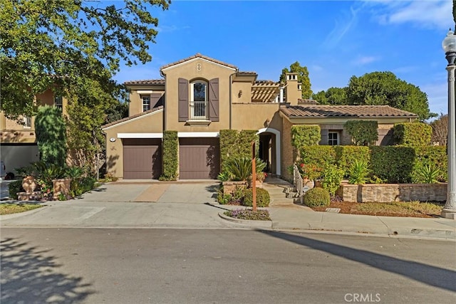 mediterranean / spanish home with stucco siding, a garage, concrete driveway, and a tile roof