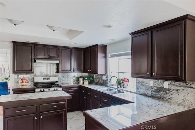 kitchen with dark brown cabinetry, sink, stainless steel stove, and decorative backsplash