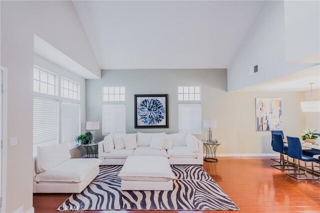 living room with hardwood / wood-style flooring, a wall unit AC, and high vaulted ceiling