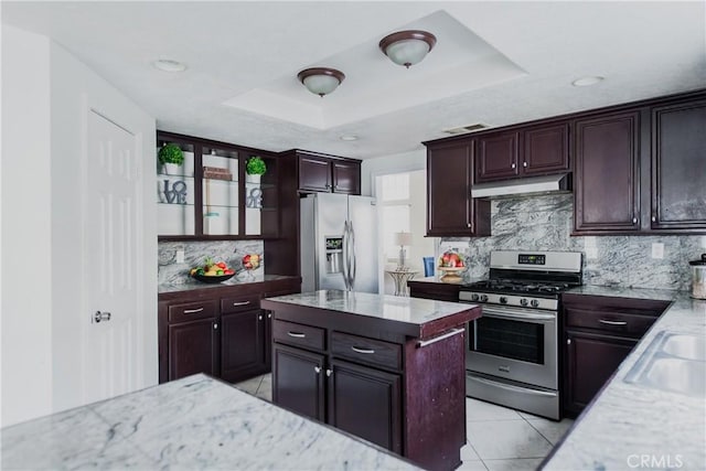 kitchen with backsplash, a center island, light tile patterned floors, a tray ceiling, and stainless steel appliances