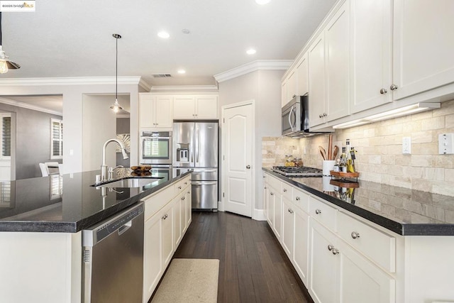 kitchen featuring appliances with stainless steel finishes, white cabinetry, sink, hanging light fixtures, and a center island with sink