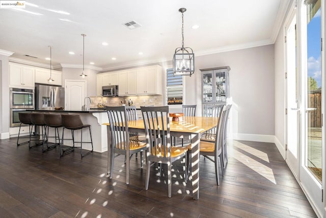 dining space with ornamental molding, dark hardwood / wood-style floors, and sink