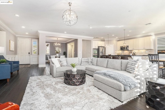 living room featuring crown molding, dark wood-type flooring, and an inviting chandelier