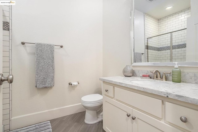 bathroom with vanity, a shower with door, and toilet