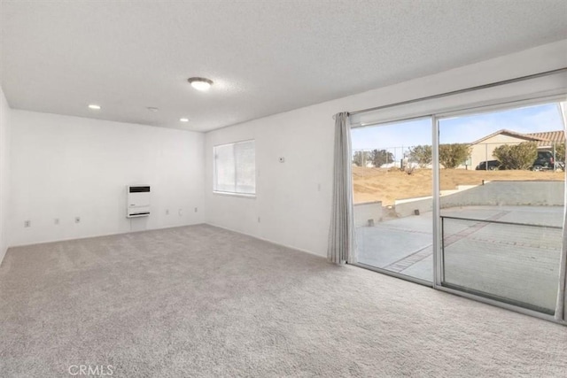 carpeted empty room with heating unit and a textured ceiling