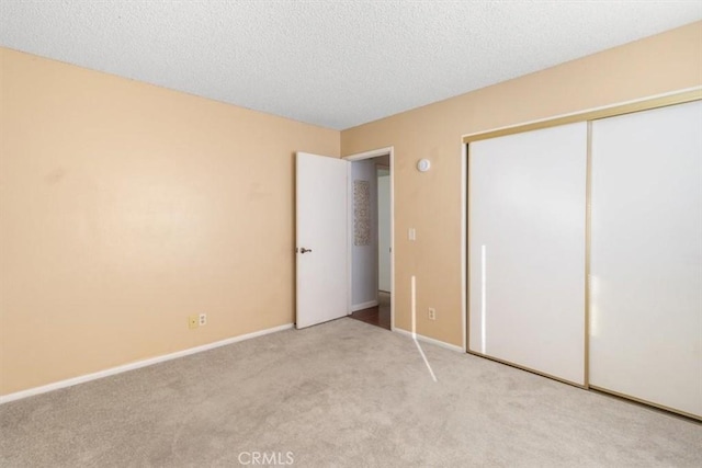 unfurnished bedroom featuring light carpet, a textured ceiling, and a closet