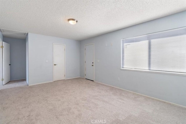 empty room with light colored carpet and a textured ceiling