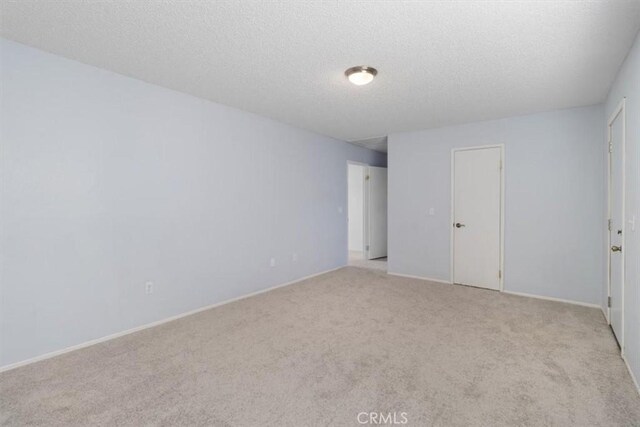 empty room featuring light colored carpet and a textured ceiling