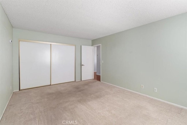 unfurnished bedroom featuring light colored carpet, a closet, and a textured ceiling