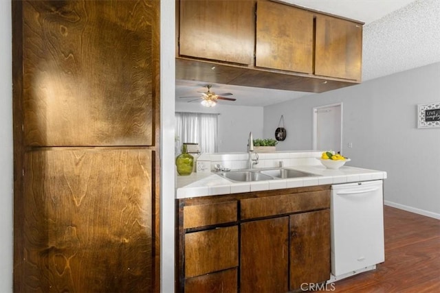 kitchen featuring sink, dark hardwood / wood-style flooring, tile counters, ceiling fan, and white dishwasher