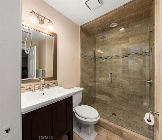 bathroom featuring toilet, vanity, a shower with door, tile patterned flooring, and backsplash