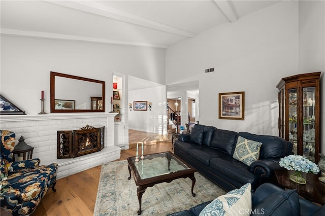 living room featuring lofted ceiling with beams and light hardwood / wood-style flooring