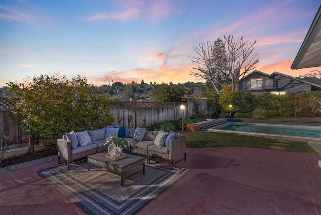 patio terrace at dusk with a fenced in pool and an outdoor living space